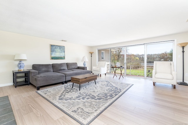 living room with visible vents, light wood-type flooring, and baseboards