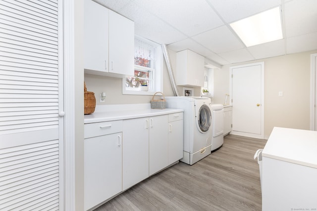 washroom with separate washer and dryer, cabinet space, and light wood-style flooring