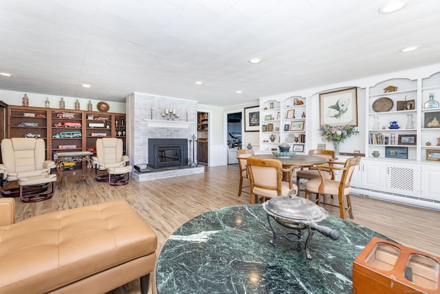 living area featuring recessed lighting, wood finished floors, and a large fireplace