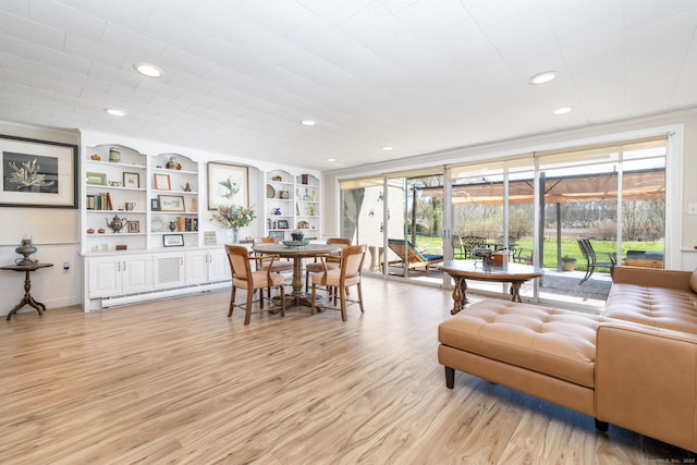 living room with light wood-type flooring, recessed lighting, built in features, and a baseboard radiator