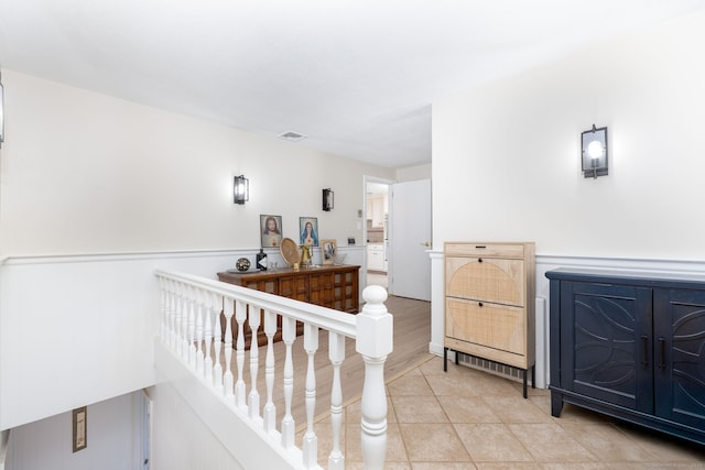 hallway featuring light tile patterned floors and an upstairs landing