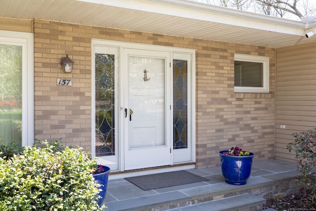 entrance to property with brick siding and a porch