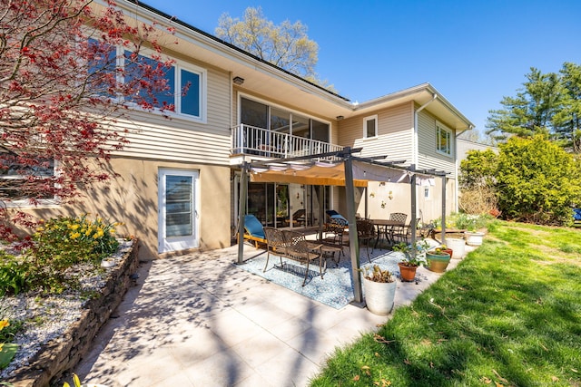 rear view of house featuring stucco siding, a yard, a balcony, and a patio