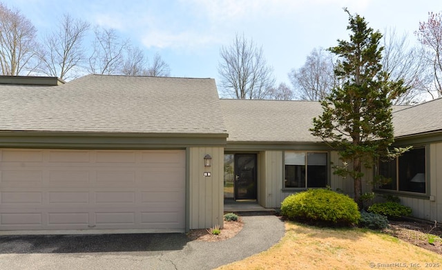 view of front of home featuring roof with shingles, driveway, and a garage