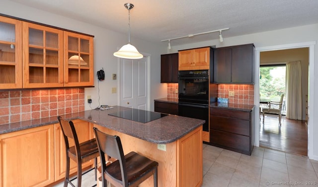 kitchen featuring a kitchen bar, black appliances, decorative backsplash, and glass insert cabinets