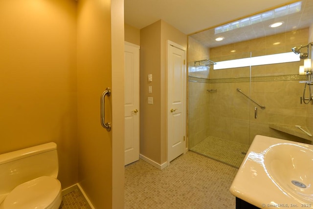 bathroom with a shower stall, tile patterned floors, vanity, baseboards, and toilet