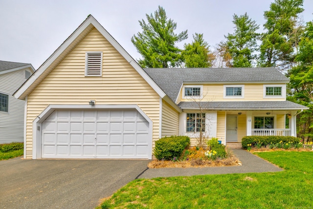 traditional-style house with covered porch, driveway, a garage, a front lawn, and a shingled roof