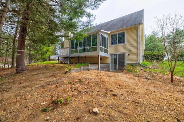 rear view of house featuring roof with shingles and a sunroom