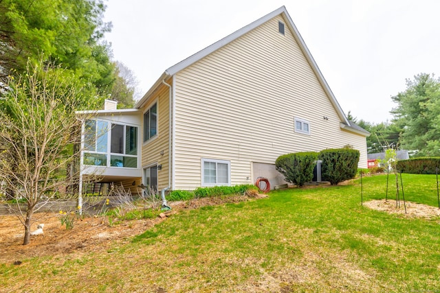 view of side of home with a lawn, a chimney, and a sunroom