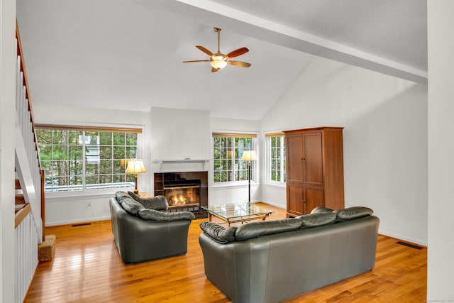 living area featuring visible vents, baseboards, ceiling fan, a tile fireplace, and light wood finished floors