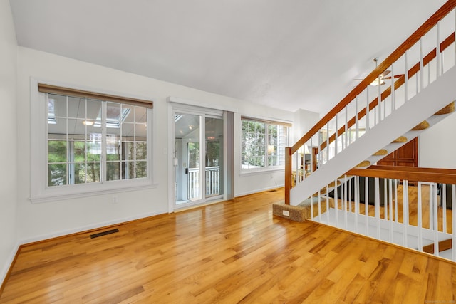 unfurnished living room with stairway, baseboards, a ceiling fan, and wood finished floors