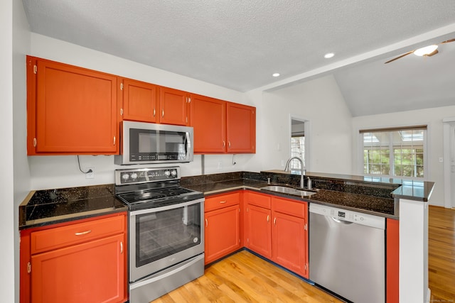 kitchen featuring a sink, appliances with stainless steel finishes, light wood-type flooring, and a peninsula
