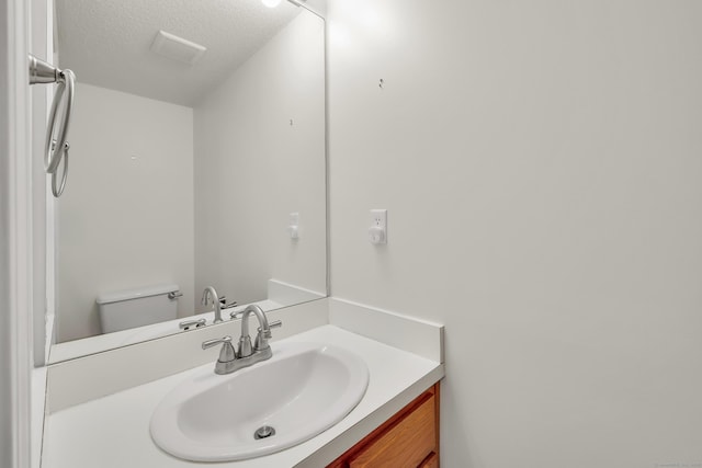 bathroom with vanity, toilet, and a textured ceiling