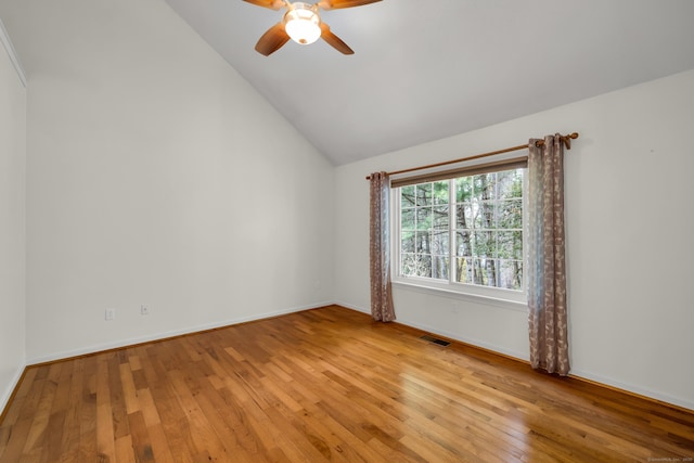 spare room with ceiling fan, visible vents, vaulted ceiling, baseboards, and light wood-style flooring