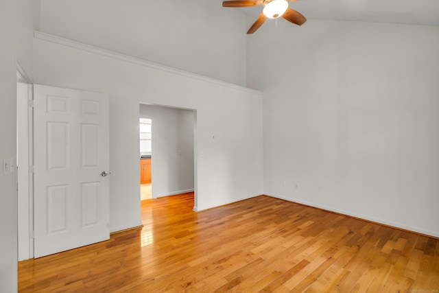 unfurnished room with light wood-type flooring, a ceiling fan, baseboards, and a towering ceiling