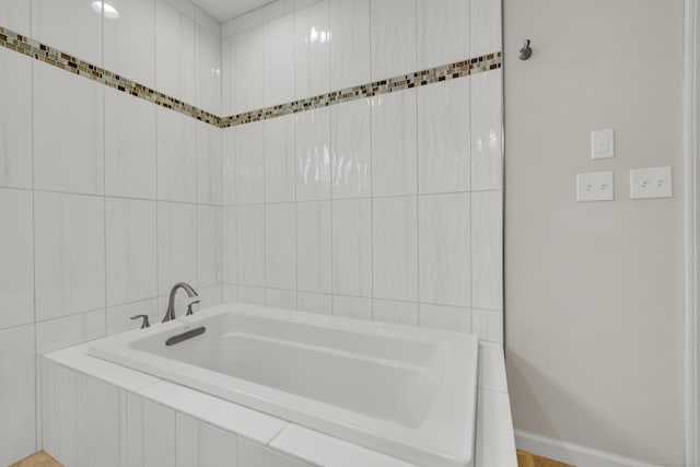 bathroom featuring baseboards and a bath