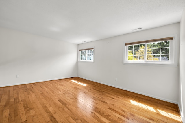 empty room with light wood-style floors, baseboards, and visible vents