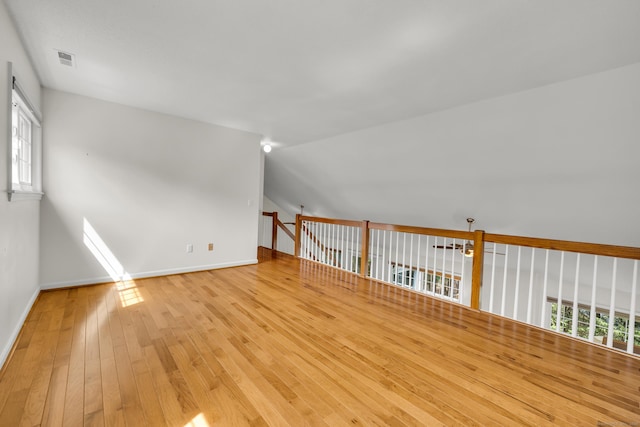 additional living space with baseboards, visible vents, lofted ceiling, and hardwood / wood-style floors