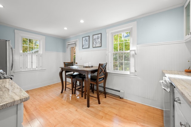 dining room featuring a baseboard heating unit, plenty of natural light, wainscoting, and light wood-style floors