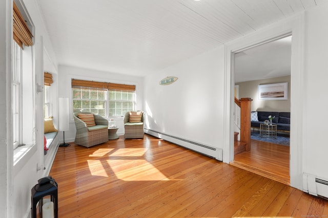 living area with stairway, a baseboard radiator, and light wood-style flooring