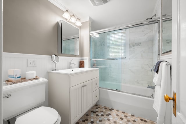bathroom featuring tile patterned floors, a wainscoted wall, shower / bath combination with glass door, toilet, and vanity