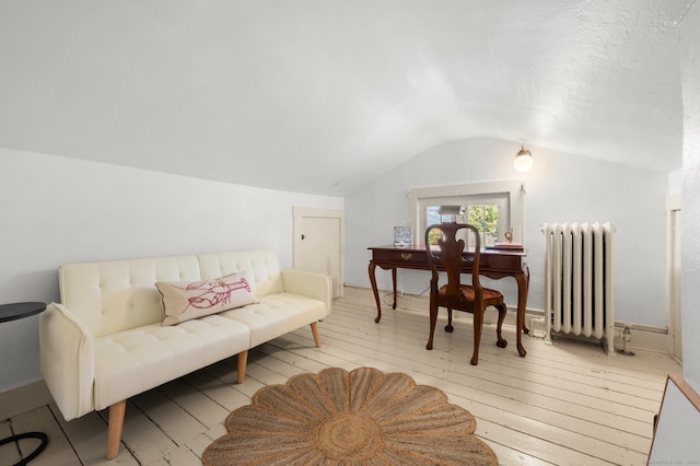 sitting room with radiator heating unit, lofted ceiling, and hardwood / wood-style flooring
