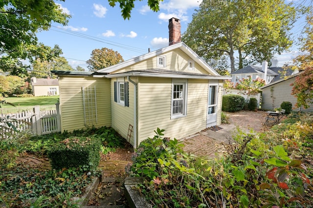 view of home's exterior with a chimney, fence, and a patio