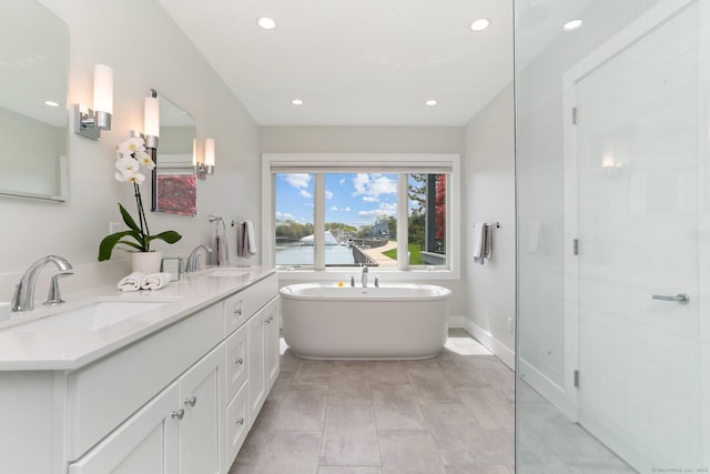 full bathroom featuring recessed lighting, a freestanding bath, a sink, and a water view