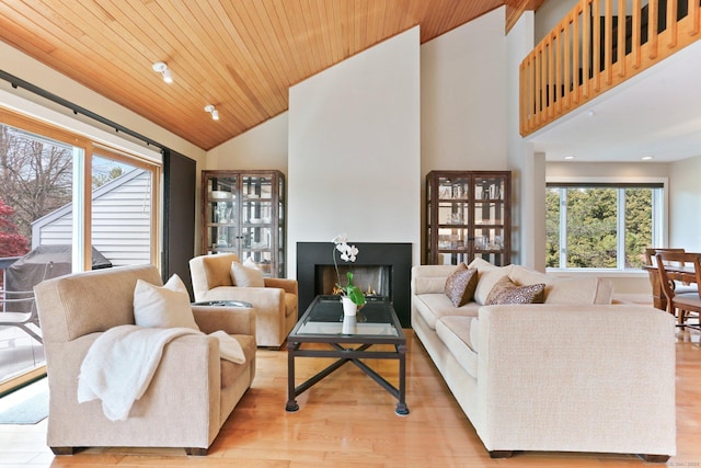 living area with high vaulted ceiling, wooden ceiling, wood finished floors, and a fireplace