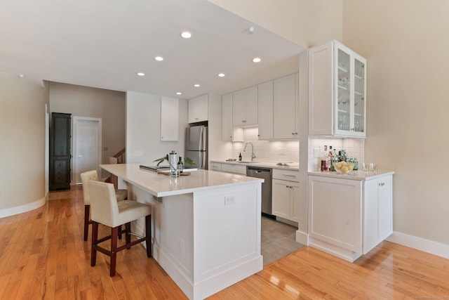 kitchen with a sink, light countertops, stainless steel appliances, white cabinetry, and decorative backsplash