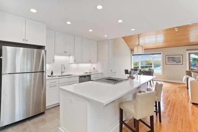 kitchen featuring a sink, stainless steel appliances, recessed lighting, white cabinetry, and a kitchen island