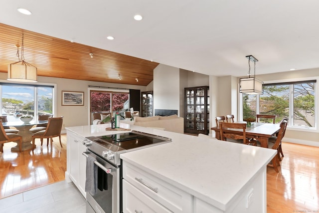 kitchen with a center island, recessed lighting, white cabinets, light stone counters, and stainless steel range with electric cooktop