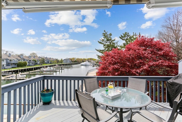 wooden deck featuring outdoor dining area, a boat dock, and a water view