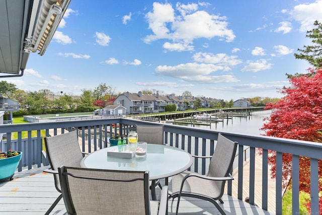 wooden deck with a water view, a residential view, and outdoor dining area
