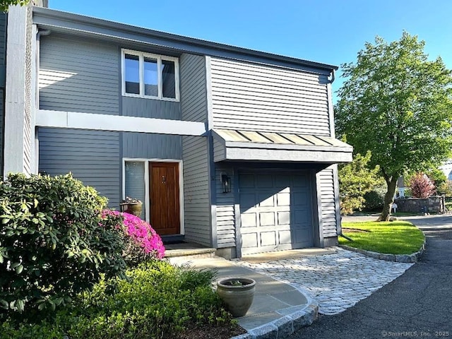 view of front of house with a standing seam roof, an attached garage, and driveway