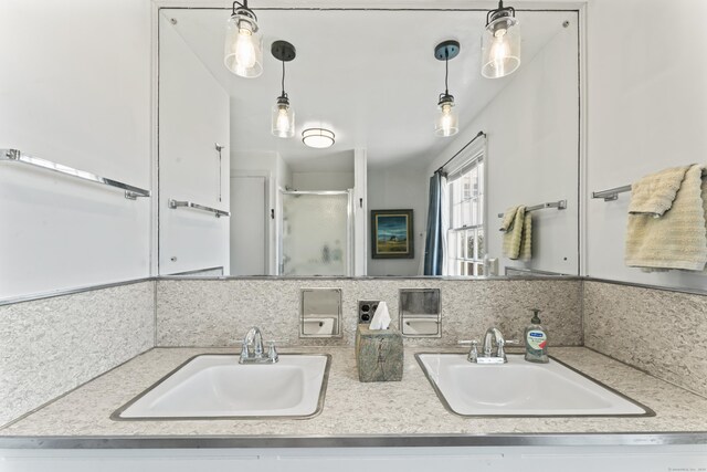full bathroom with double vanity, a shower stall, decorative backsplash, and a sink
