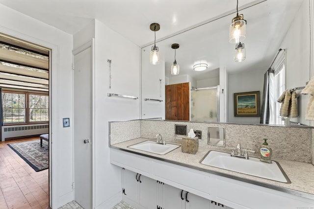 bathroom featuring a shower with door, double vanity, decorative backsplash, and a sink