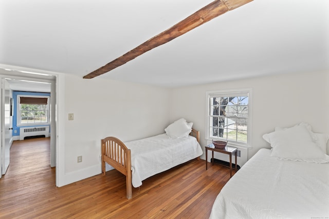 bedroom featuring wood-type flooring, radiator, beam ceiling, and baseboards