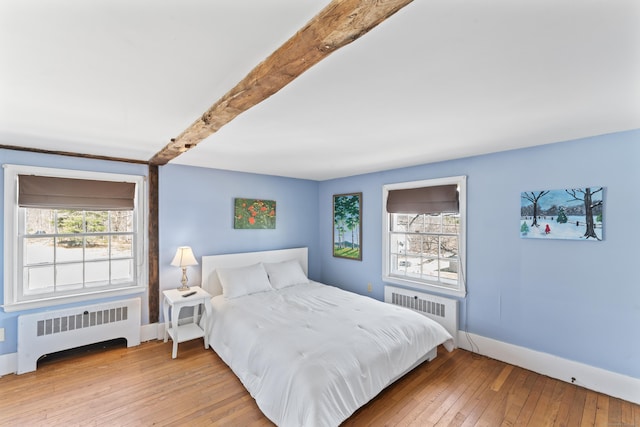 bedroom featuring radiator heating unit, baseboards, hardwood / wood-style floors, and beamed ceiling