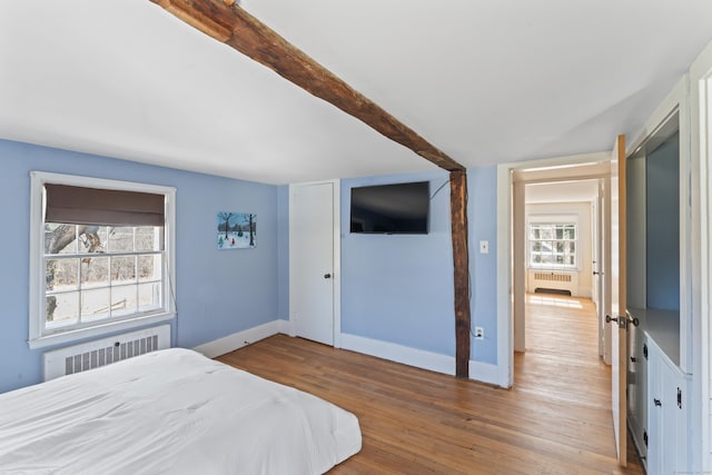 bedroom featuring wood finished floors, baseboards, and radiator
