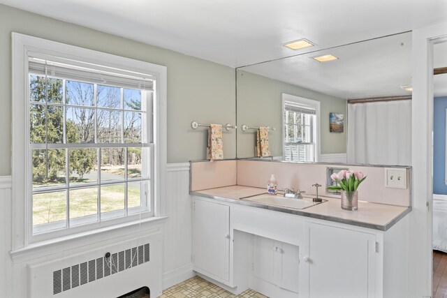bathroom with radiator heating unit, a wainscoted wall, and vanity