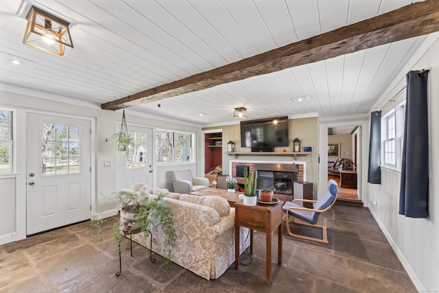 living area featuring a fireplace, plenty of natural light, beam ceiling, and baseboards