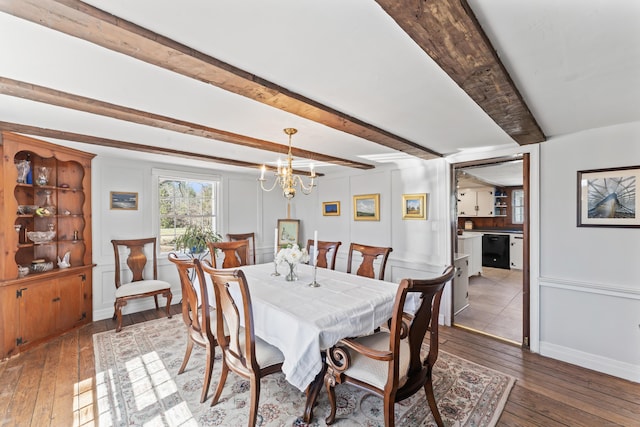 dining space featuring beam ceiling, an inviting chandelier, a decorative wall, and wood-type flooring