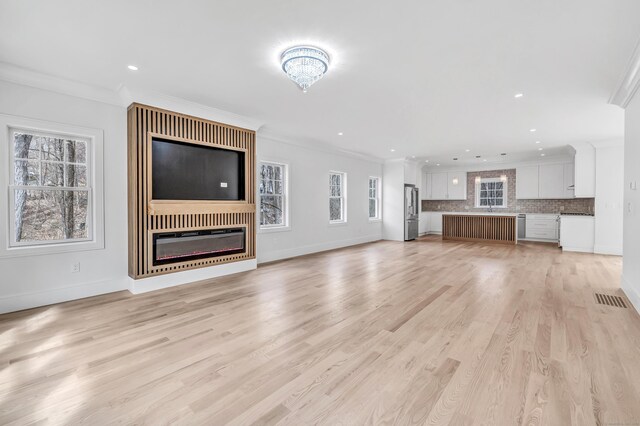 8 Fox Run, Monroe, CT 06468 - unfurnished living room featuring a glass covered fireplace, crown molding, plenty of natural light, light wood finished floors, and baseboards