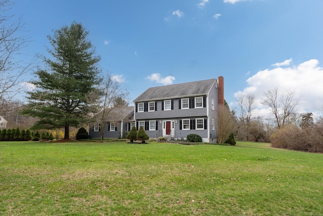 colonial house featuring a chimney and a front lawn