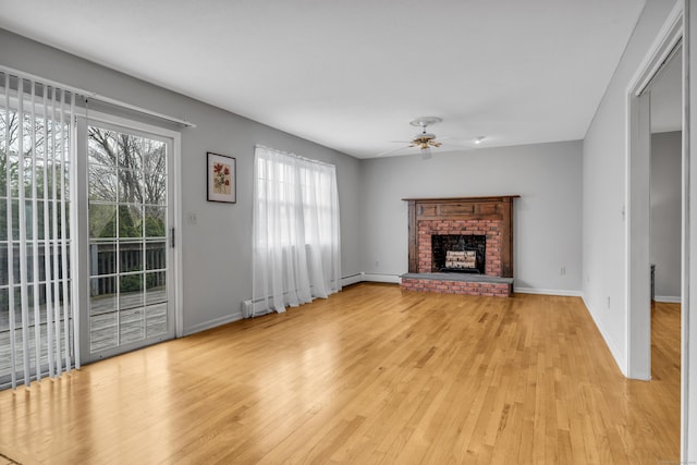 unfurnished living room with light wood-type flooring, baseboards, a brick fireplace, and ceiling fan