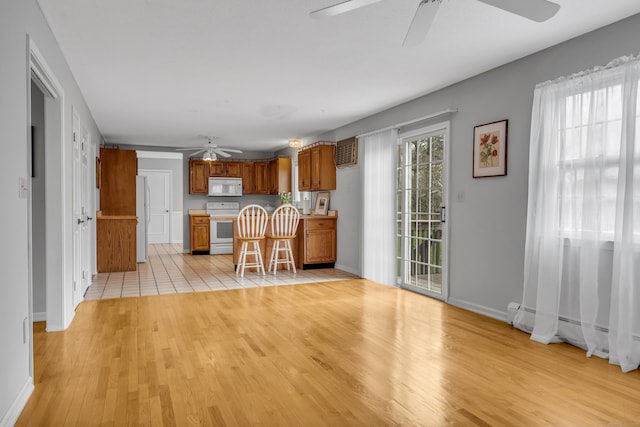 kitchen with brown cabinets, light wood-style floors, ceiling fan, and white appliances