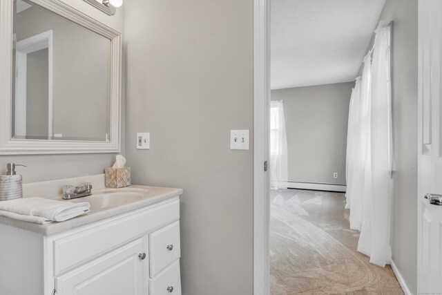 bathroom with baseboards, vanity, and a baseboard radiator