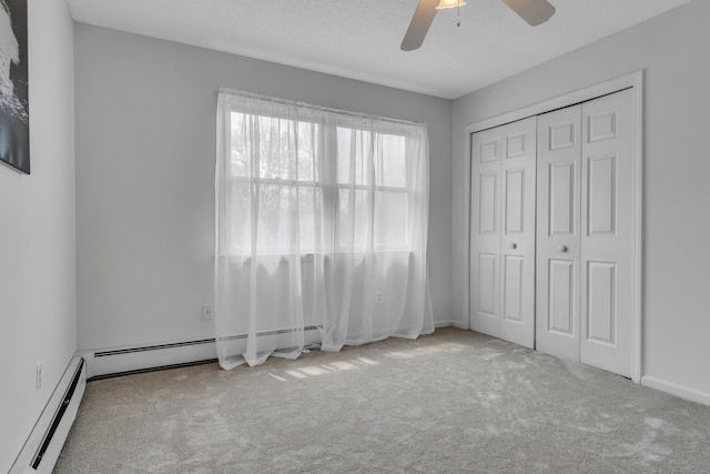 unfurnished bedroom featuring baseboard heating, carpet flooring, a closet, and ceiling fan
