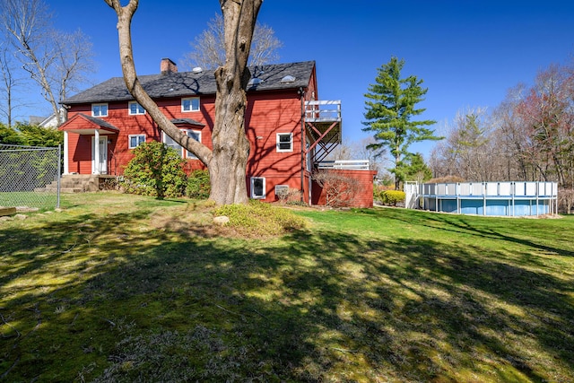 back of house with a chimney, fence, a yard, and a fenced in pool